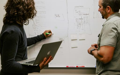 2 people planning at the whiteboard.